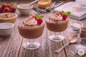 Keto chocolate mousse topped with whipped cream, raspberries, and chocolate shavings