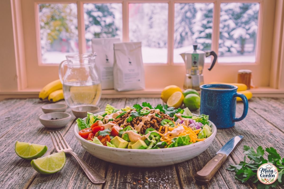 Keto taco salad with seasoned ground beef, avocado, cheddar cheese and fresh vegetables