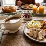 Homemade Thanksgiving turkey gravy in a gravy boat beside roast turkey and mashed potatoes