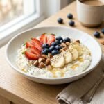 Healthy cottage cheese bowl topped with strawberries, blueberries, banana, chopped nuts, chia seeds, and honey