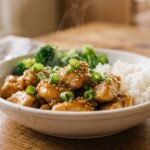 Slow cooker honey garlic chicken coated in a glossy sweet and savory sauce with green onions and sesame seeds